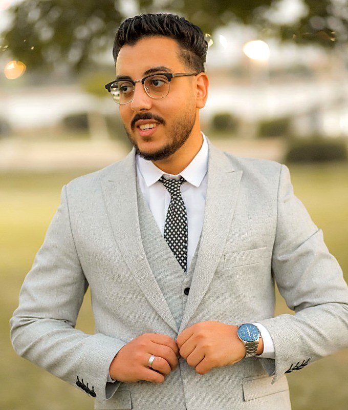 Sayed Elmahdy in a light grey suit, smiling, outdoors at golden hour